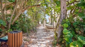 A pathway lined with trees and a wooden trash bin. - Beach Livin 5BR  Walk to Beach ~ Rooftop Deck ~3 Kitchens (Treasure Island)