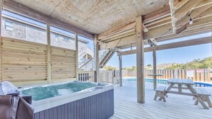Una terrazza in legno con idromassaggio, ringhiere di legno e zona piscina.