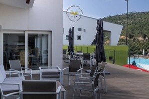 Eine Hotelterrasse mit Sitzgelegenheiten, Sonnenschirmen und einem Pool.