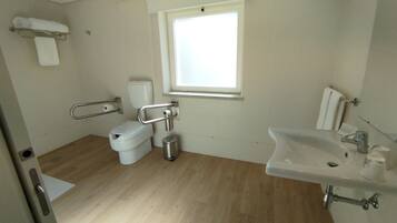 Un baño con inodoro, bidé, lavabo y ventana.