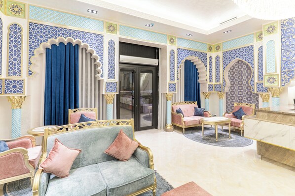 En luksuriøs lobby med detaljeret blå og gylden udsmykning, bløde siddepladser og en elegant receptionsdisk i marmor.