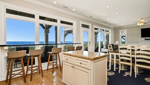 A kitchen with a large island, bar stools, and a view of the ocean. - Lighthouse: Oceanfront with Pool and Elevator Near Fishing Pier (Oak Island)