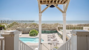 A wooden deck with a pool and lounge chairs overlooking the beach and ocean. - Lighthouse: Oceanfront with Pool and Elevator Near Fishing Pier (Oak Island)