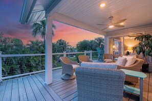Terraza exterior techada con mobiliario de mimbre y vista al atardecer.
