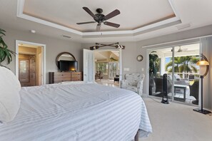 Une chambre dotée d’un grand lit, d’un ventilateur de plafond, d’une commode et donnant sur le patio extérieur.