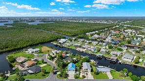 An aerial view of a residential area with houses, a river, and a distant cityscape.