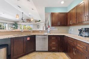 Una cocina moderna con armarios de madera oscura, lavavajillas de acero inoxidable y encimera de mármol.