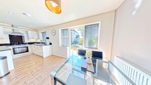 A modern kitchen with a central island, built-in oven, and a dining area with a glass table.