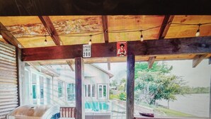 Ein überdachter Außenbereich mit Grill, Geschwindigkeitsbegrenzungsschild und Blick auf ein Haus und Bäume.