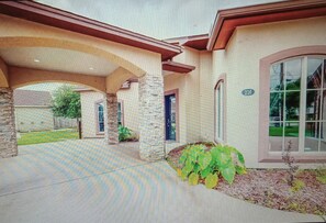 Une maison avec un porche couvert, des piliers en pierre et le numéro « 216 » inscrit sur le mur.