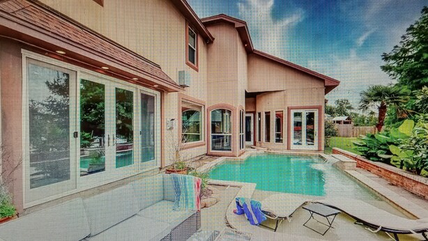 Ein Haus mit Swimmingpool, großen Fenstern und einer Terrasse mit Liegestühlen.