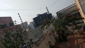 Un quartier résidentiel avec une clôture blanche, un arbre aux feuilles vertes et un bâtiment à la façade sombre.