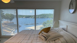 A bedroom with a bed, pillows, and a view of a body of water through large windows. - Osage Beach Condo getaway! (Osage Beach)