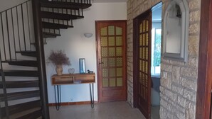 A staircase leading to a landing with a wooden console table, a decorative door, and a stone wall. - Gite en Provence capacité 6 personnes (Entressen)