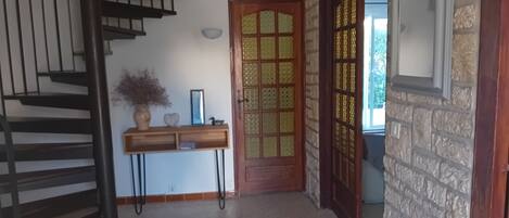 A staircase leading to a landing with a wooden console table, a decorative door, and a stone wall.