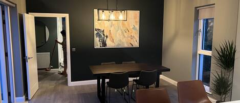A modern dining area with a dark wall, a wooden dining table, and black chairs.