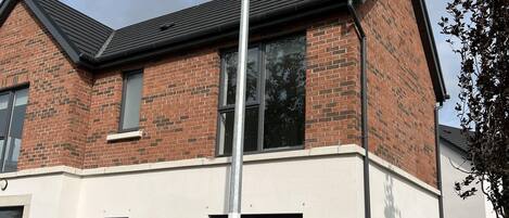 Een modern huis met twee verdiepingen, een gevel van baksteen, grote ramen en een zichtbare garage.