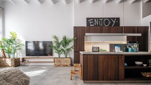 A modern kitchen with a wooden island, a flat-screen TV, and a sign that says "ENJOY".