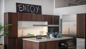 A modern kitchen with dark wood cabinets, a stainless steel refrigerator, and a central island.
