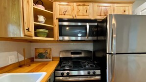 Une cuisine dotée de meubles en bois, d’un réfrigérateur en acier inoxydable, d’un four à micro-ondes et d’une cuisinière à gaz.