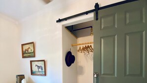 Une pièce dotée d’un plancher en bois, d’une porte coulissante, d’un porte-manteau fixé au mur et d’une armoire ornée de panneaux décoratifs.