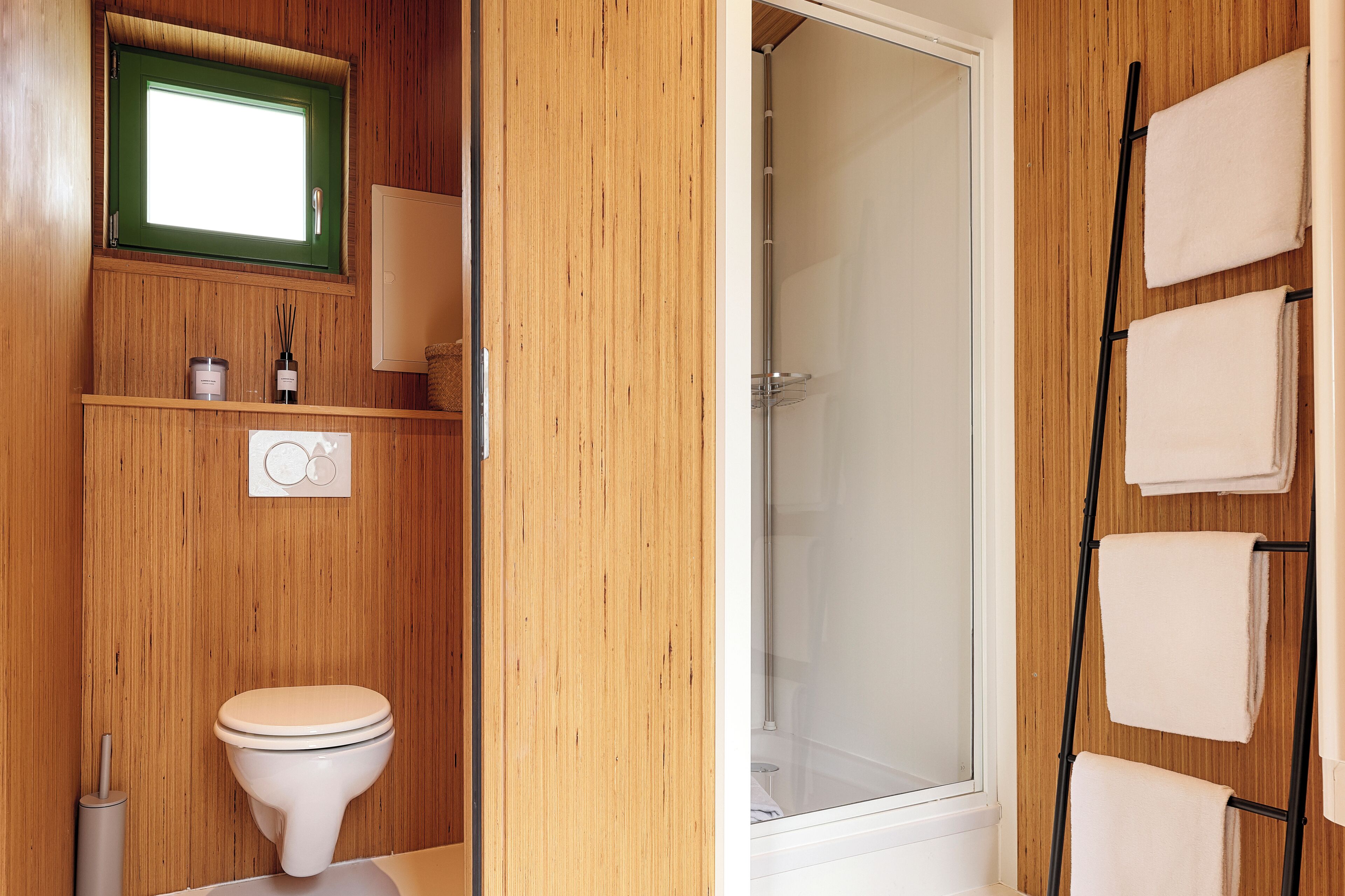 Une salle de bain en bois équipée de toilettes, d’un porte-serviettes et d’une douche.