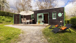 A modern outdoor dining area with a table and chairs, a barbecue grill, and lounge chairs. - homie stay radapartment (Iphofen)