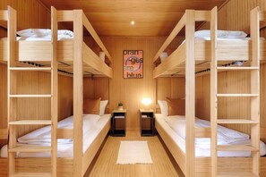 Dormitorio con literas, paredes de madera y una lámpara central.