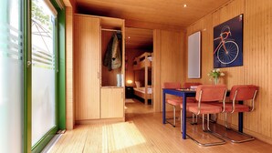 A room with wooden walls and floors, a bunk bed, a table with chairs, and a bicycle poster. - homie stay radapartment (Iphofen)