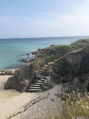 A coastal path with steps leading down to the beach, surrounded by rocky terrain and vegetation. - Maison Refaite et Lumineuse, vue Mer, à 5 Minutes de la Plage (Plogoff)