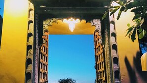 An open archway with intricate carvings, leading to a building with a yellow facade. - Deogarh Hills A Village Experience Property (Deogarh Madaria)