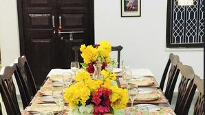 A dining table set with floral centerpieces, white plates, and wine glasses. - Deogarh Hills A Village Experience Property (Deogarh Madaria)