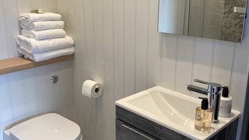 Un baño moderno con inodoro, lavamanos con espejo y un perchero para toallas.