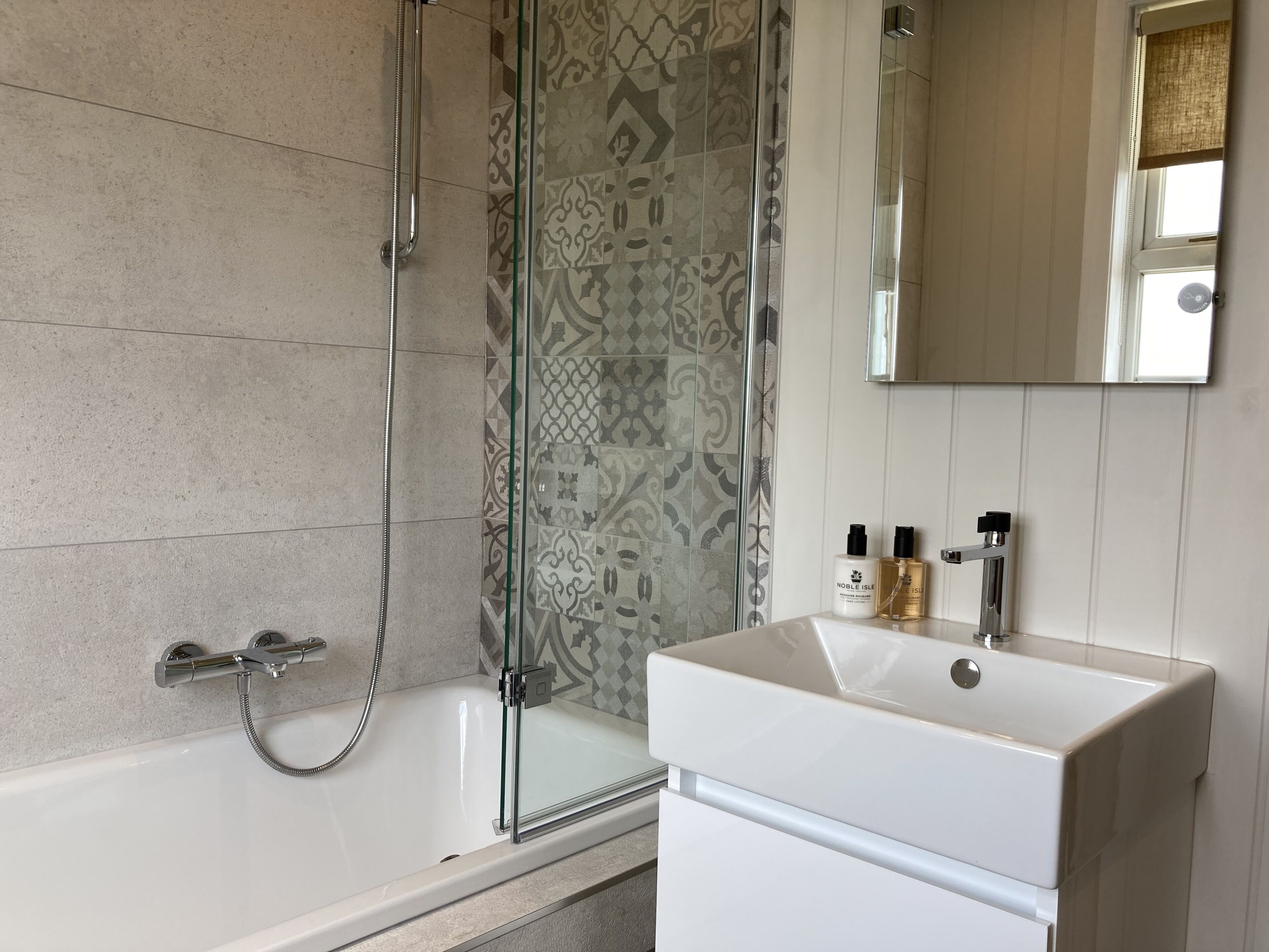 A bathroom with a bathtub, shower, and a sink with a mirror above it.