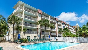 Un hotel con piscina, varios balcones y palmeras.