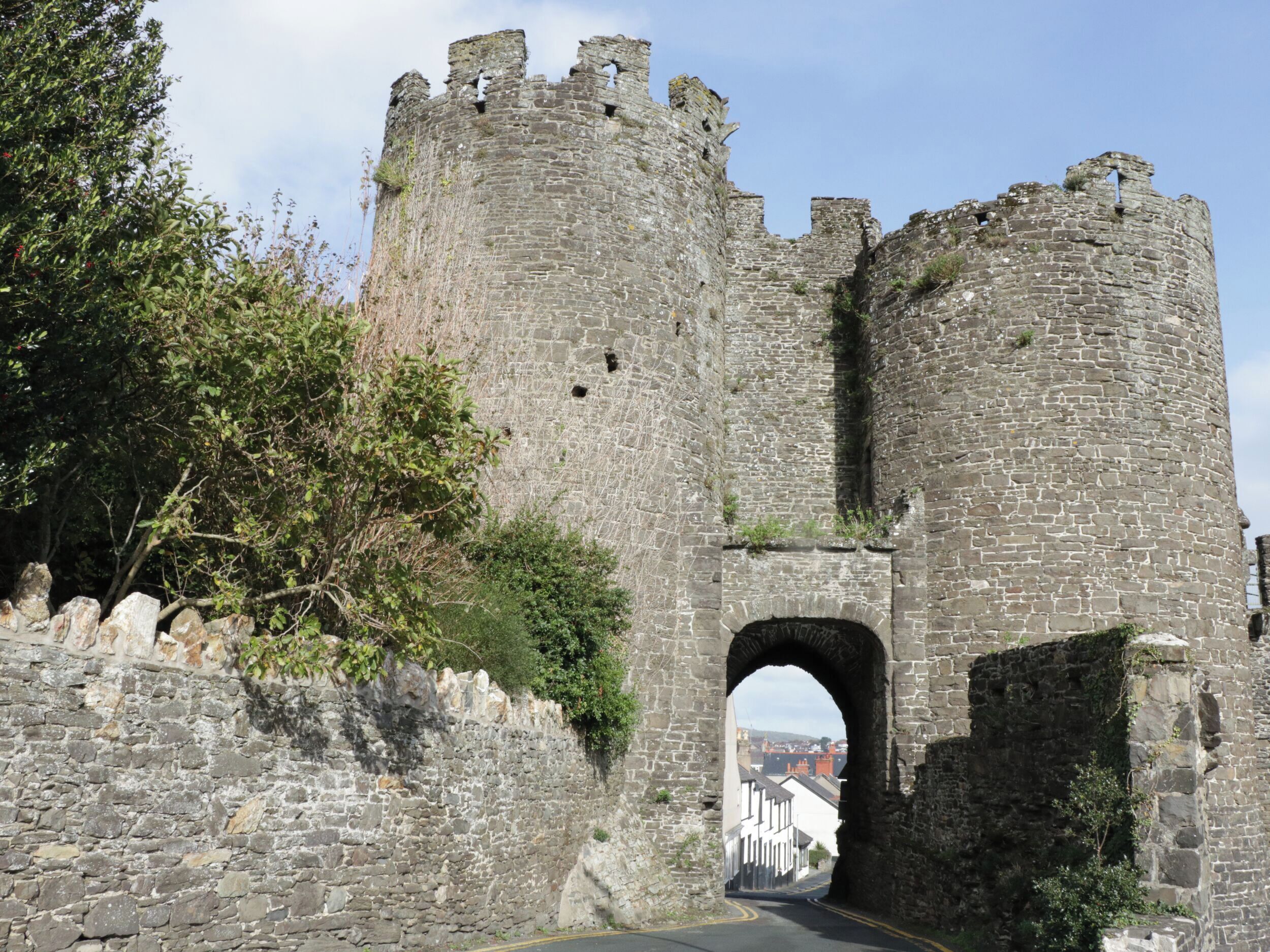 A stone castle with a large archway leading into a town.