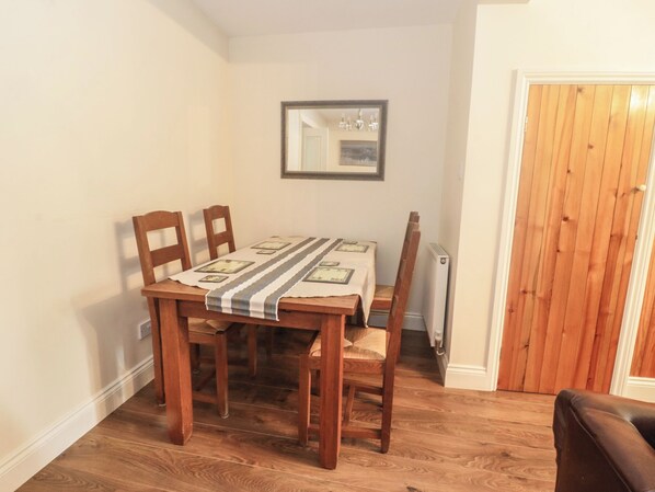 A dining area with a wooden table and chairs, a striped tablecloth, and a mirror on the wall.