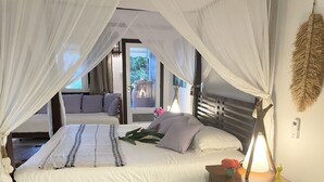 A bedroom with a bed, a nightstand, a bedside table, a lamp, and a view of the outside. - Ti Cocon de Standing (Saint-François)