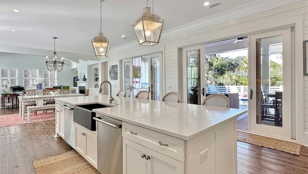 A spacious kitchen with a large island, white cabinetry, and pendant lighting.