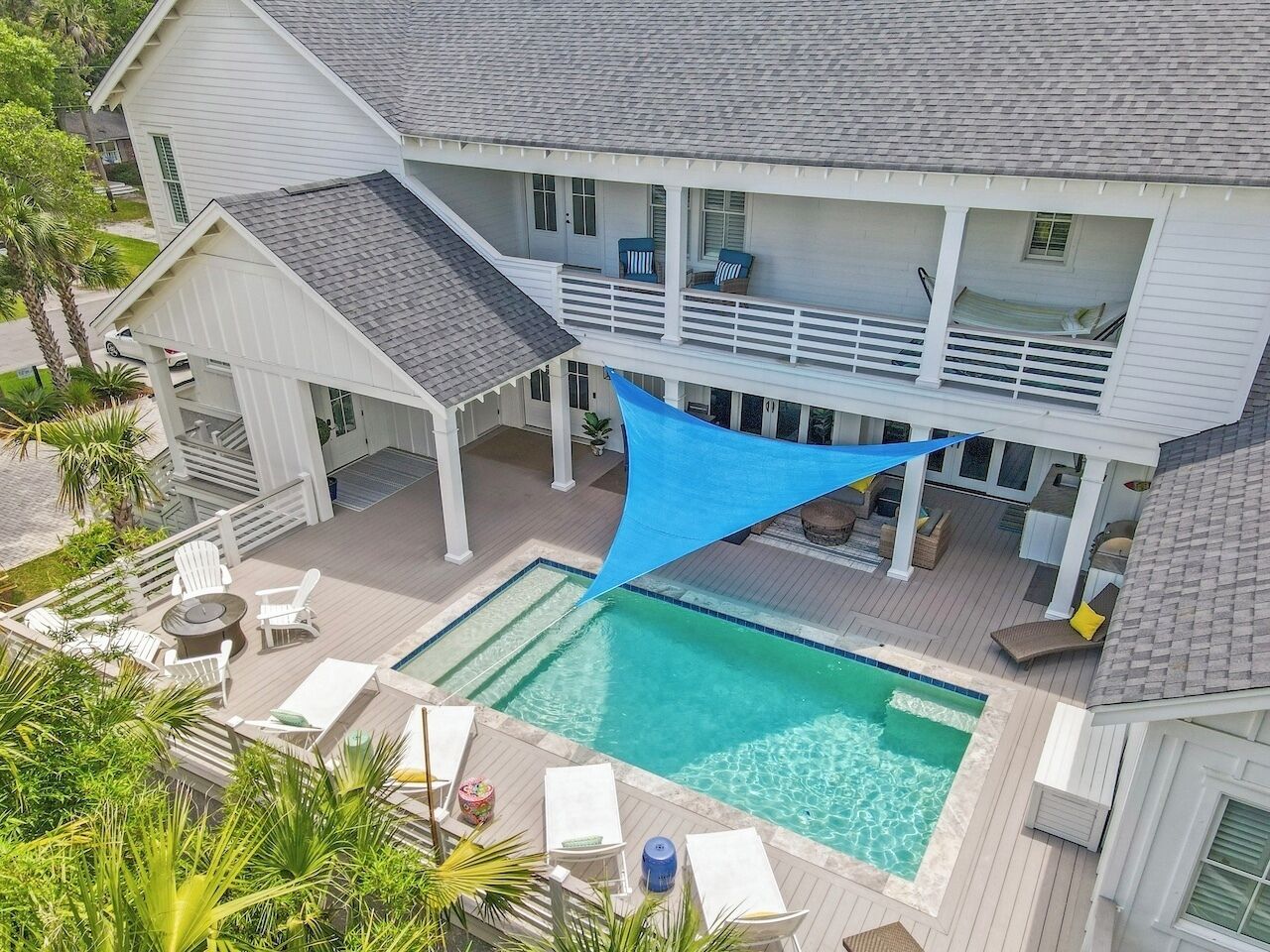 Ein zweistöckiges Haus mit Schwimmbad, Sitzgelegenheiten im Freien und einer überdachten Terrasse.
