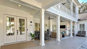 A covered patio with a dining area, a pool, and a second-story balcony.