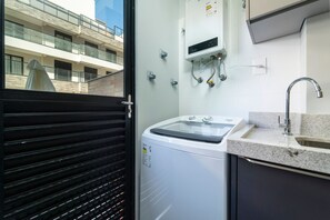 Een moderne wasruimte met een voorlader wasmachine, een inbouwgootsteen en een boiler.