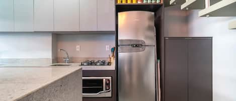 A modern kitchen with a built-in oven, a stainless steel refrigerator, and a gas stove.