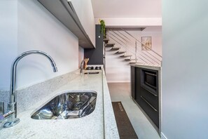 Una cocina moderna con un lavamanos de acero inoxidable, un microondas y una escalera que conduce a un nivel superior.