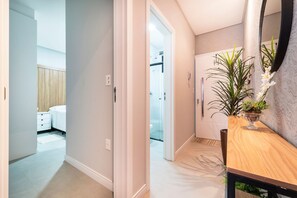 Un baño moderno con ducha de vidrio, tocador de madera y una planta en maceta.