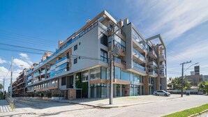A multi-story hotel with a modern architectural design, featuring balconies and large windows. - 864C Duplex 80 mts Mar Canto Grande SC (Bombinhas)