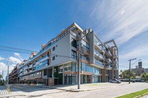 Un hotel de varios pisos con un diseño arquitectónico moderno, con balcones y grandes ventanales.