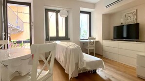 A room with a bed, a desk, a chair, a TV, and a balcony. - Appartamento Il Bottaio (Domodossola)