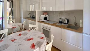 A compact kitchen with white cabinets, a microwave, a kettle, and a sink. - Appartamento Il Bottaio (Domodossola)