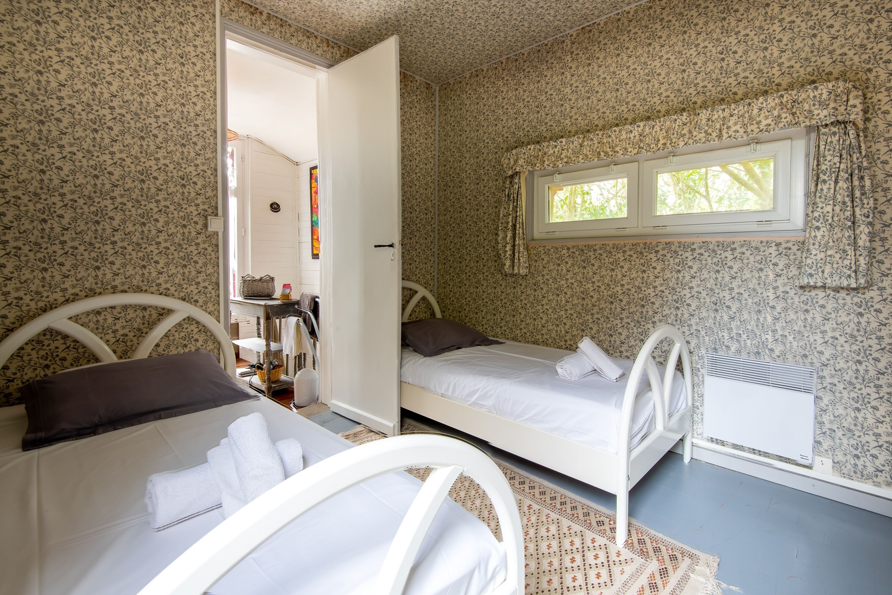 Een slaapkamer met twee bedden, een raam en een radiator.